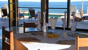 A table set for dining with a view of the beach and ocean.