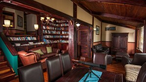 A library with leather chairs, a telescope, and bookshelves.