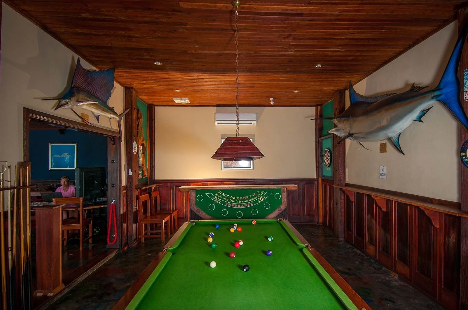 Una mesa de billar con bolas, paredes de madera y adornos de peces.