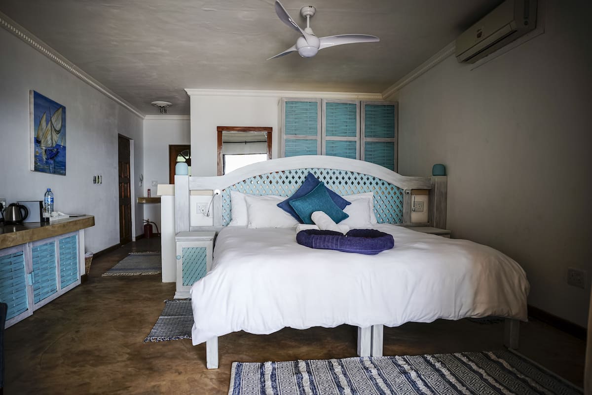 A bedroom with a bed, a ceiling fan, a nightstand, a dresser, and a painting on the wall.