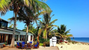 A poolside area with a wooden deck, lounge chairs, and a view of the beach and ocean.