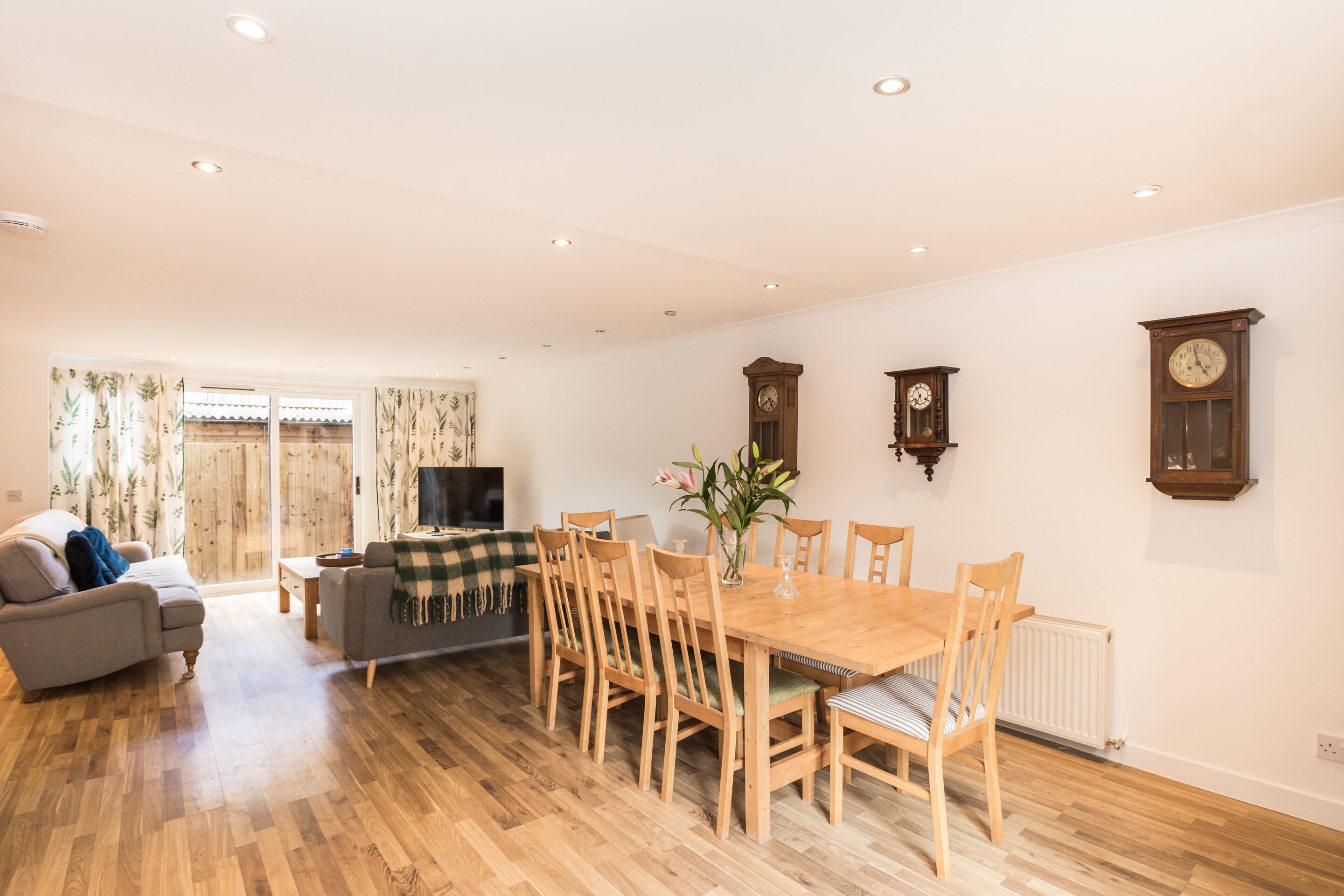 A spacious living area with a dining table, chairs, sofas, and a television.