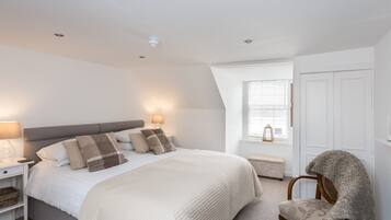 Une chambre à coucher avec un lit, des lampes de chevet, une chaise, une fenêtre et une porte.