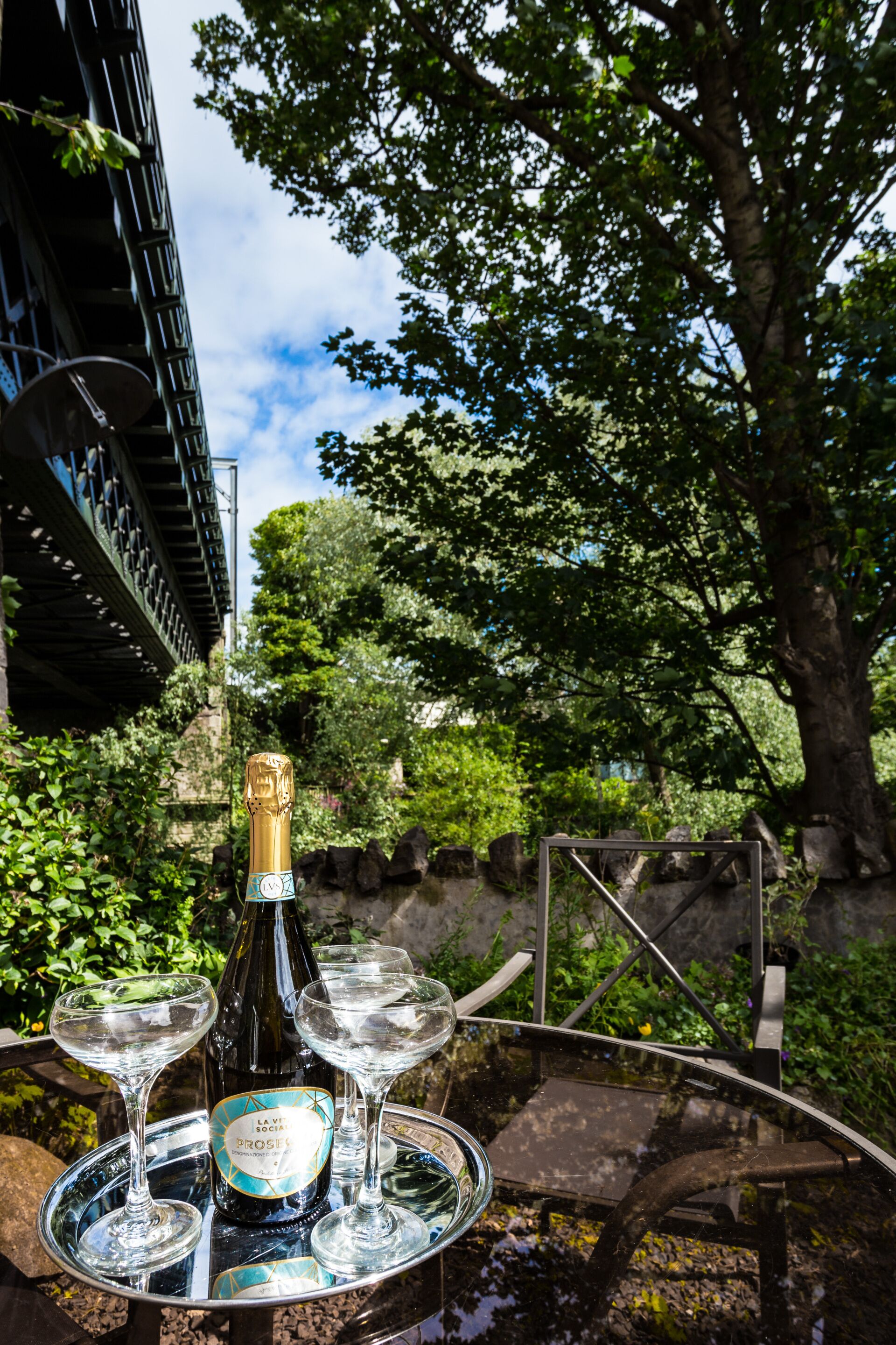 A bottle of Levitron Prosecco on a tray with three glasses.