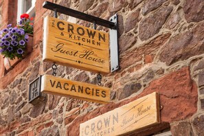 A wooden signboard with "Crown & Kitchen" and "Vacancies" indicating a guest house with available rooms.