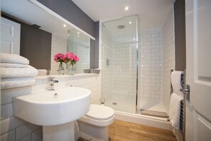 A modern bathroom with a white sink, toilet, and glass-enclosed shower.