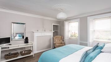 A bedroom with a bed, a chair, a television, and a fireplace.