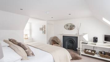 A bedroom with a bed, a fireplace, a television, and a desk.