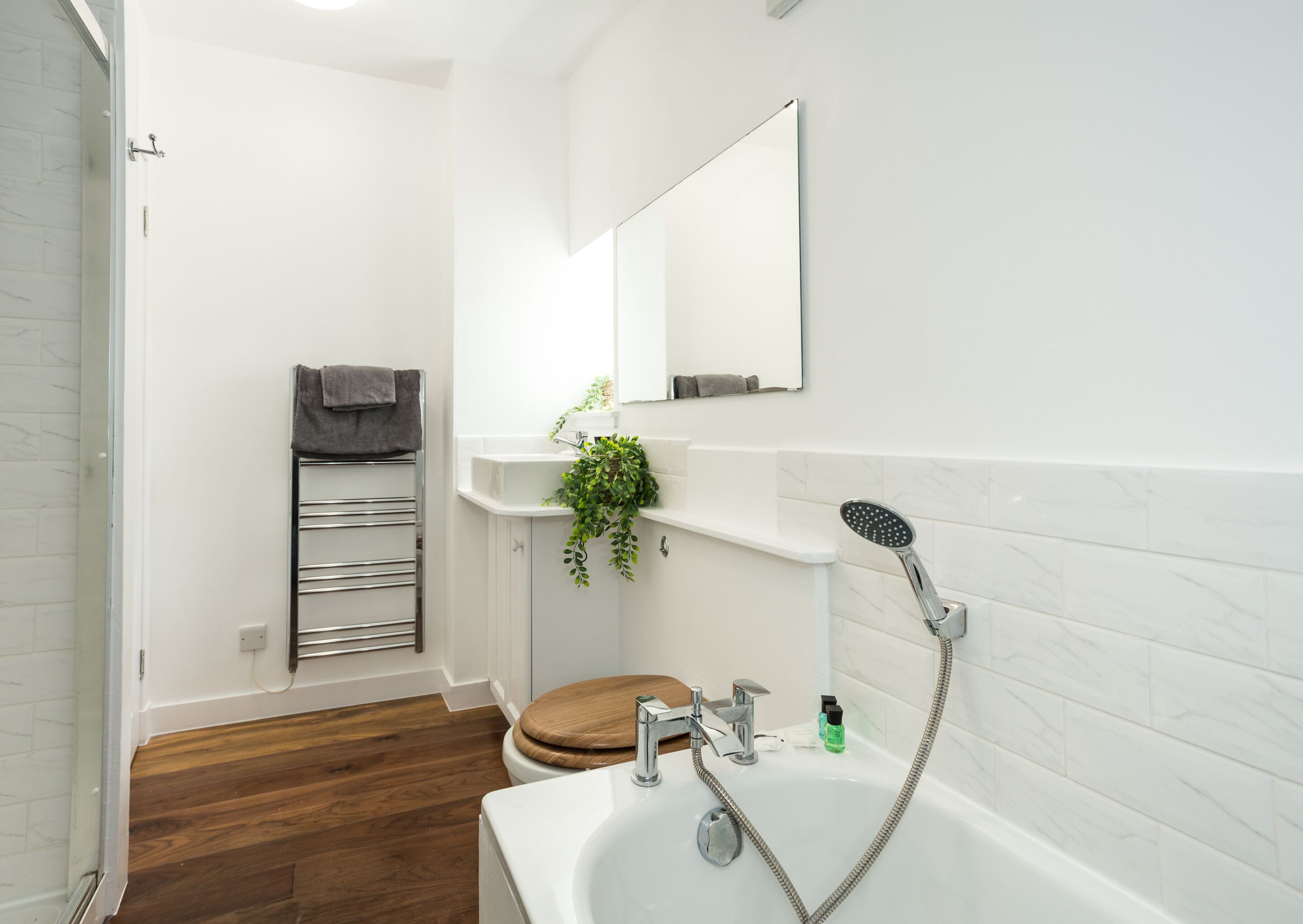 Une salle de bain moderne équipée d’une baignoire, de toilettes, d’une douche et d’un porte-serviettes.