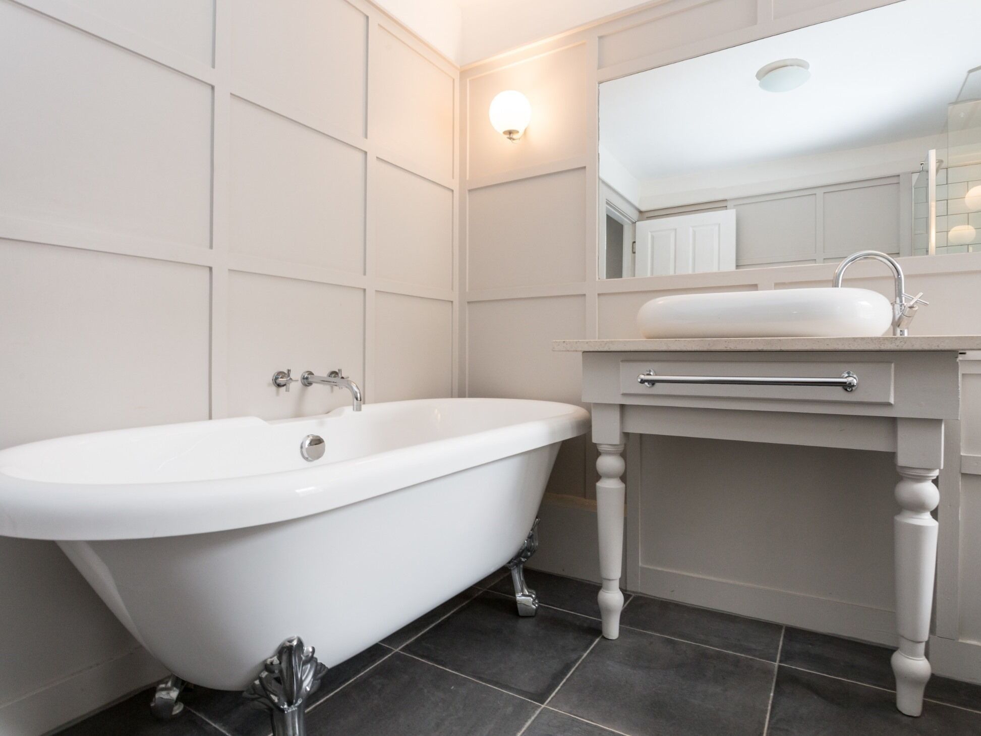 A modern bathroom with a freestanding bathtub, a vanity with a sink, and a mirror above the sink.