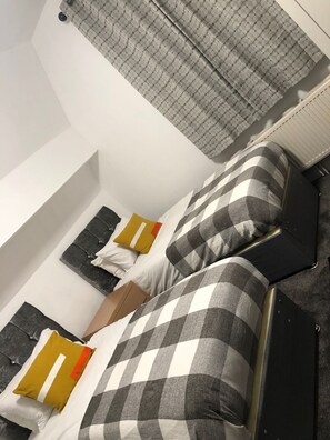 A bedroom with a bed, pillows, a nightstand, and a radiator. - Ashfield Hotel (Huddersfield)