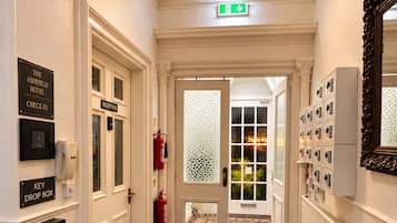 A hotel lobby with a reception desk, a key drop box, a fire extinguisher, and a check-in sign.