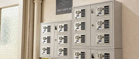 A self check-in area at The Ashfield Hotel with numbered lockers and a fire alarm call point.