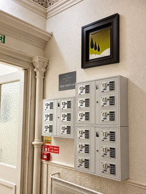 A self check-in area at The Ashfield Hotel with numbered lockers and a fire alarm call point. - Ashfield Hotel (Huddersfield)