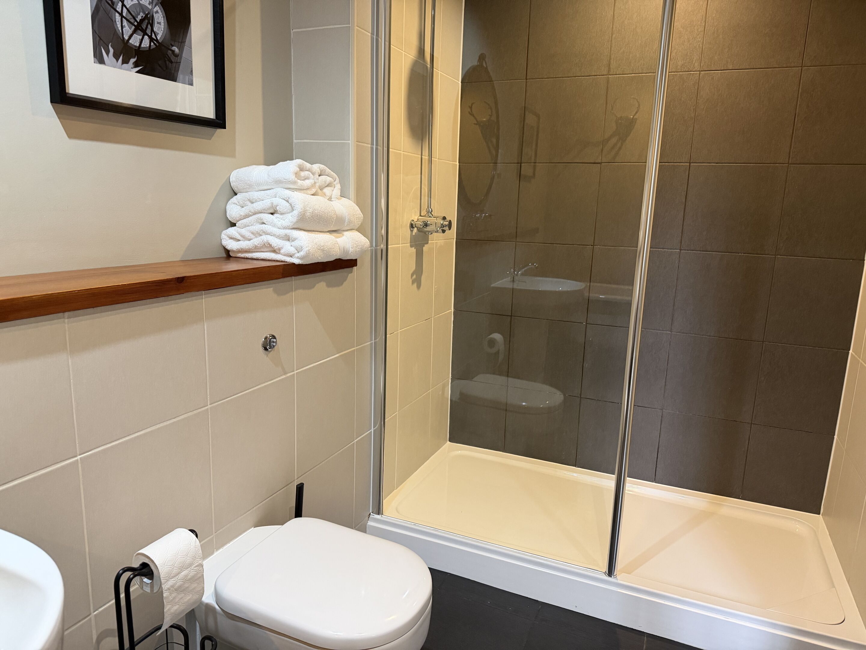 A modern bathroom with a glass-enclosed shower, a toilet, and a sink.