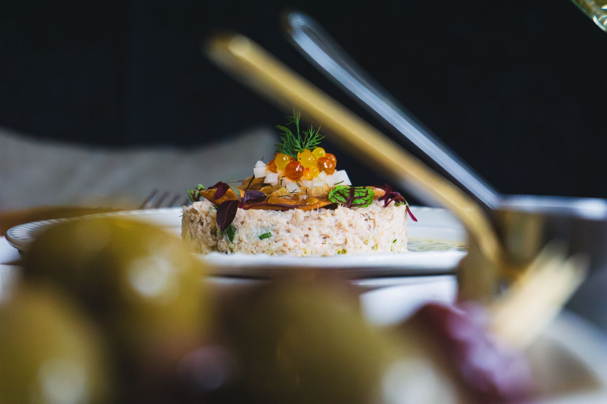 A dish with a garnish of green leaves and yellow berries on a white plate.