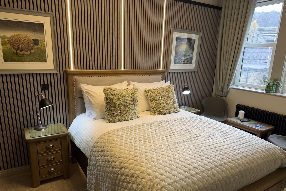 A neatly arranged hotel room with a bed, bedside tables, a lamp, and framed artwork on the walls.