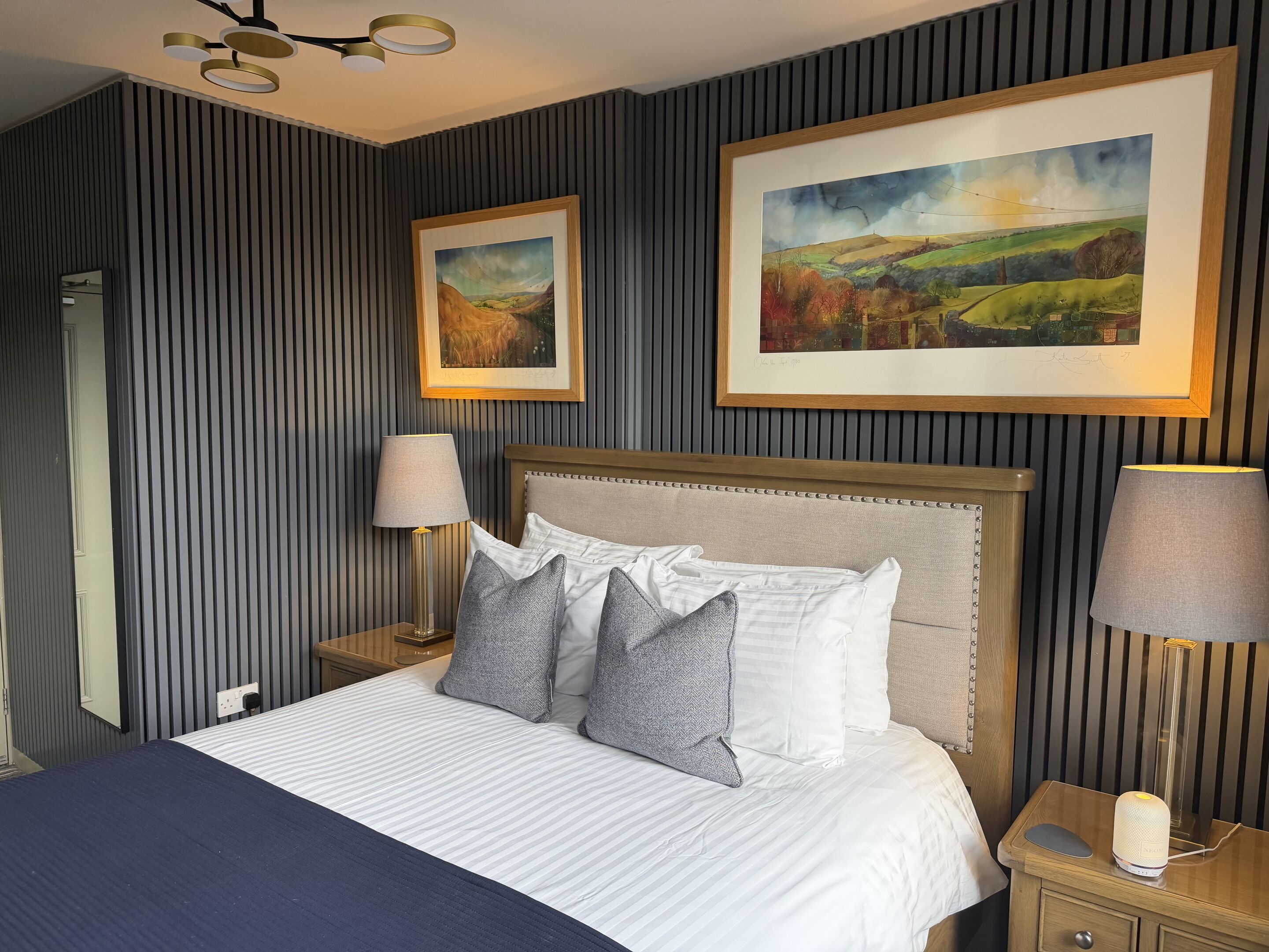A neatly made bed with striped bedding, a headboard, and two bedside lamps.
