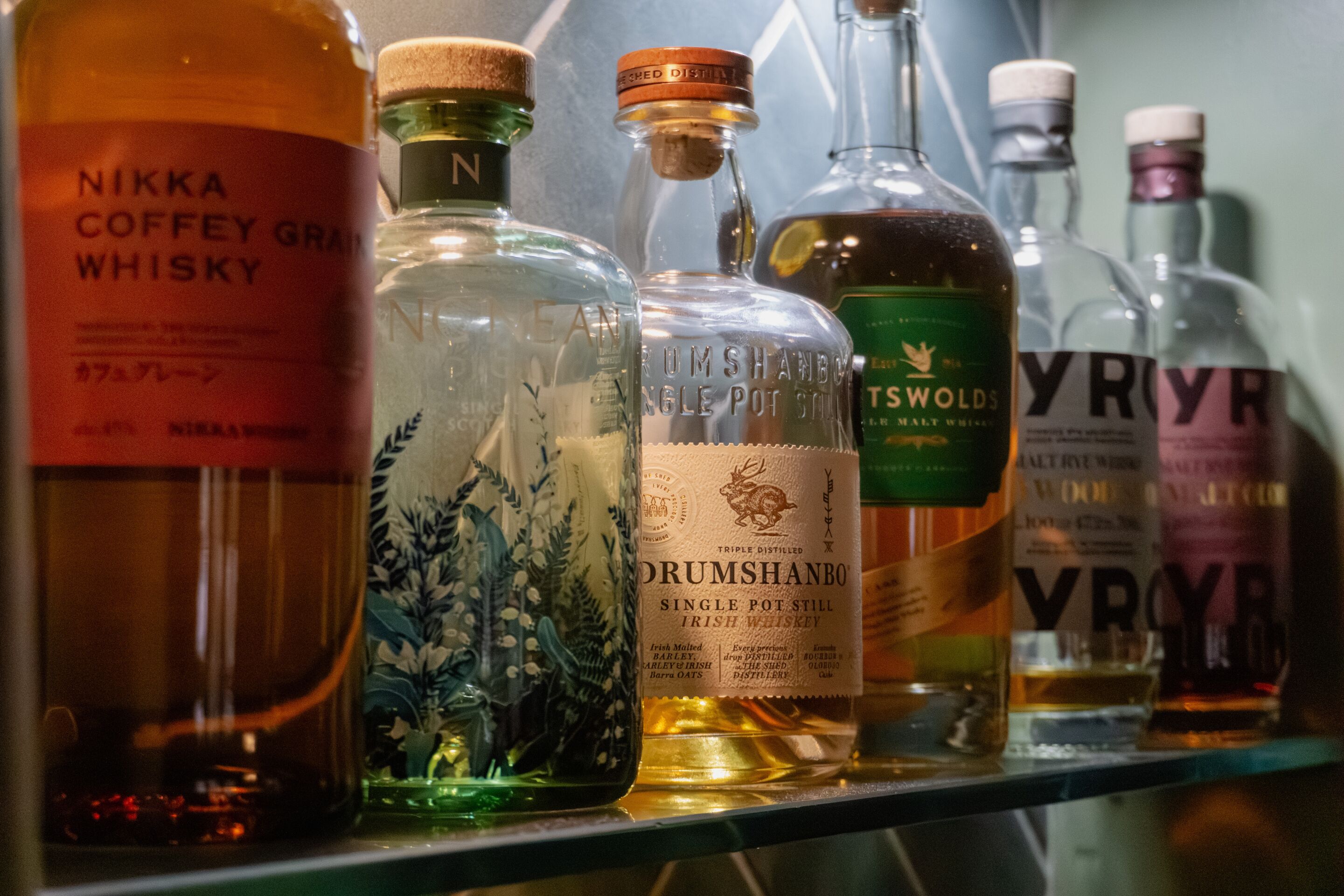 Une sélection de bouteilles de whisky présentées sur une étagère.
