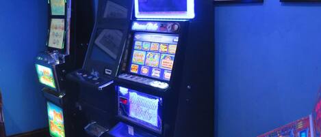 A slot machine area with multiple machines, a large screen, and framed pictures on the wall.