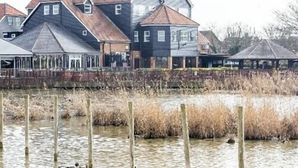 Une rangée de maisons avec un plan d’eau devant.
