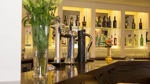 Un espace bar avec un assortiment de bouteilles d’alcool, un robinet et un vase contenant des plantes vertes.