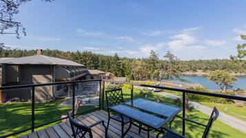 A deck with a table and chairs overlooking a lake and forested area.