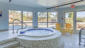 A hot tub with mosaic tile steps, large windows, and yellow chairs.