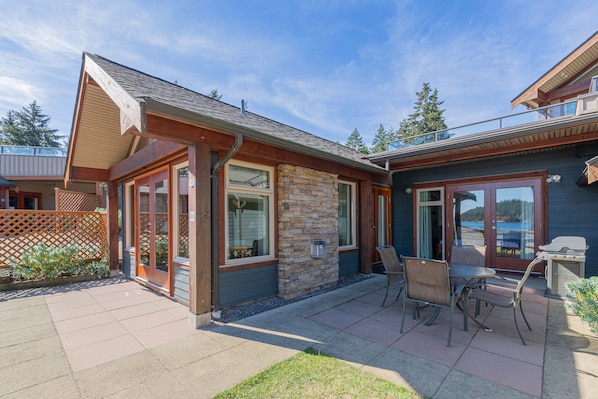 A house with a patio, stone wall, and a grill. - Mayne Island Resort (Mayne Island)