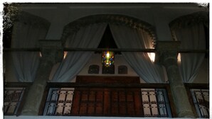 Una habitación con un arco de piedra, una puerta de madera y un vitral arriba.