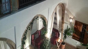 Interior con varios niveles, balcón, arcos y plantas en macetas.