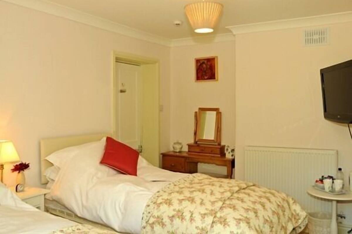 Une chambre d’hôtel équipée d’un lit, d’une table de chevet, d’une lampe et d’un téléviseur fixé au mur.