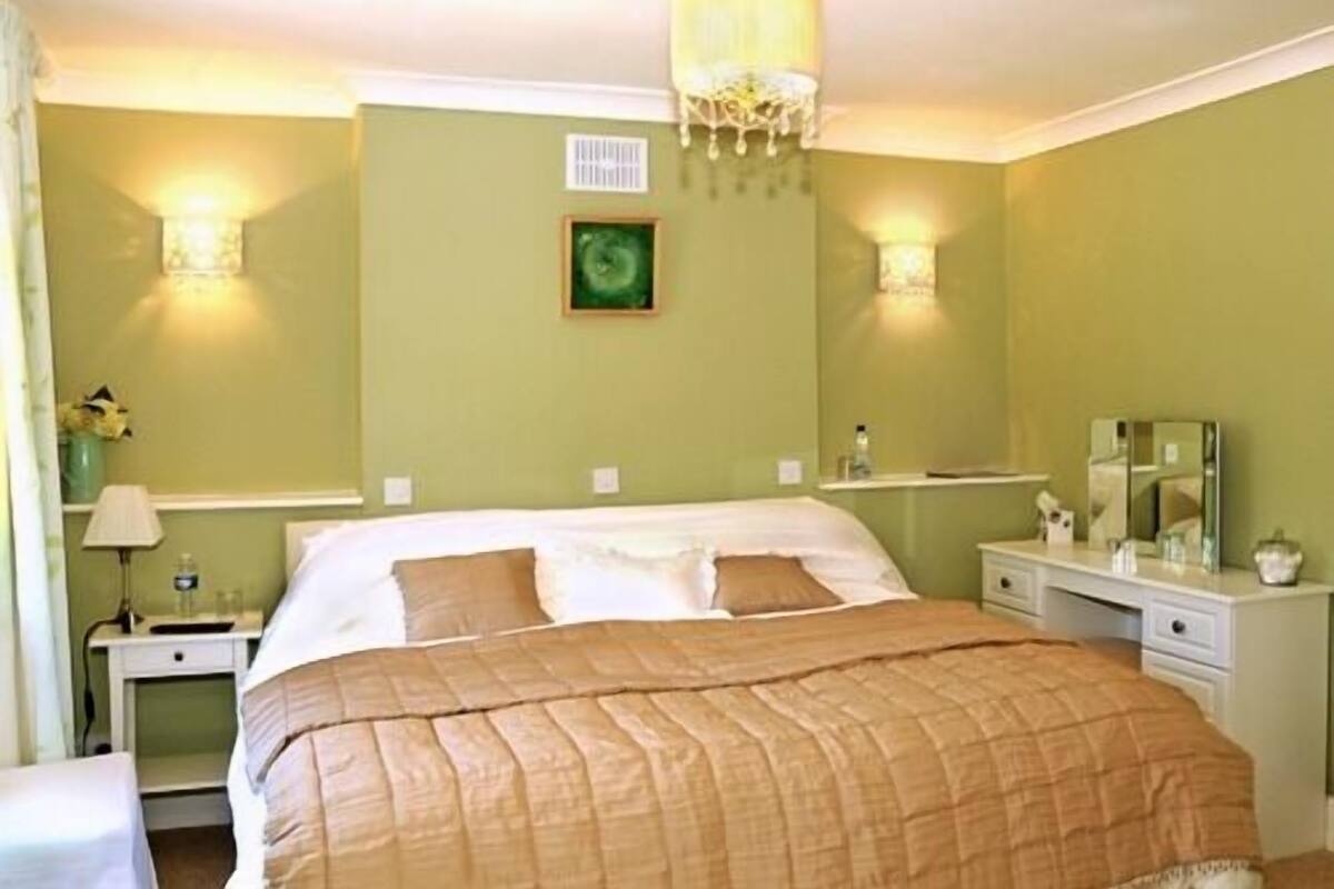 Une chambre d’hôtel équipée d’un lit, de tables de chevet, d’un miroir et de lampes fixées au mur.