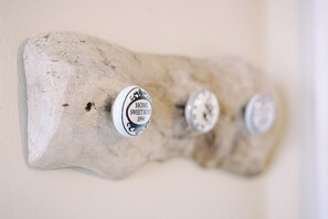 Un élément décoratif en bois à fixer au mur, orné de trois boutons en métal, chacun portant une inscription différente.