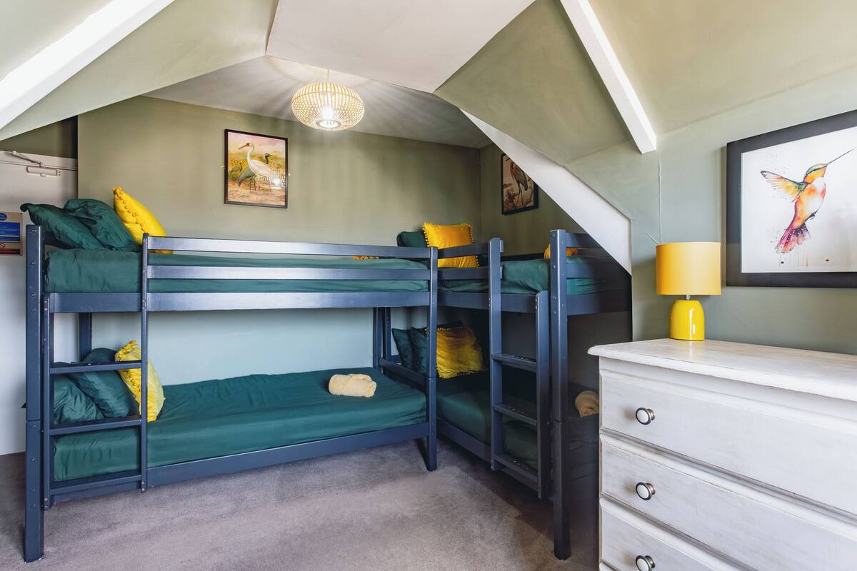 Una camera con un letto a castello, una cassettiera e una lampada.