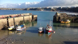 A harbor with boats docked at a pier, calm water, and a distant coastline. - Smarties Guest House (Newquay)