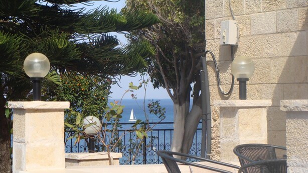 A stone balustrade with a view of the sea and a sailboat. - Tamer guest house (Haifa)