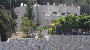 A multi-story building with a stone facade, balconies, and a mountainous backdrop. - Tamer guest house (Haifa)