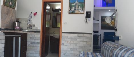 Um espaço compacto com cozinha compacta, sofá, área de refeições e banheiro.