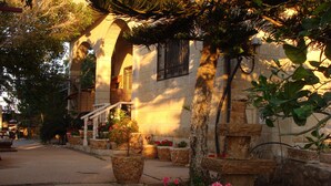 A building with stone architecture, a stone staircase, and potted plants with flowers. - Tamer guest house (Haifa)