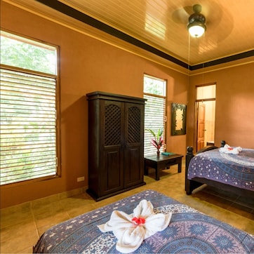 A hotel room with two beds, a wardrobe, a desk, and a lamp.