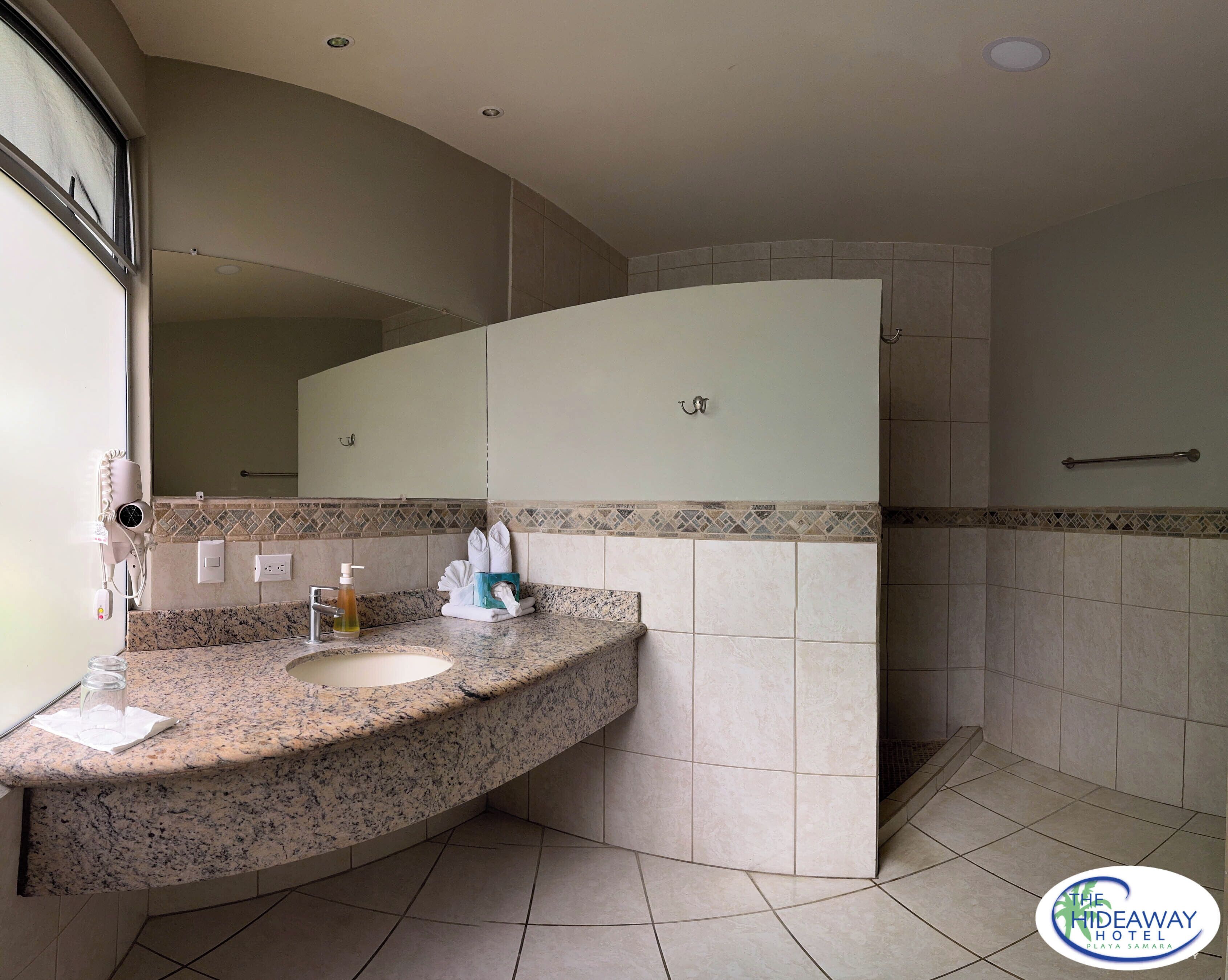 A modern bathroom with a granite countertop, a sink, a mirror, and a towel rack.