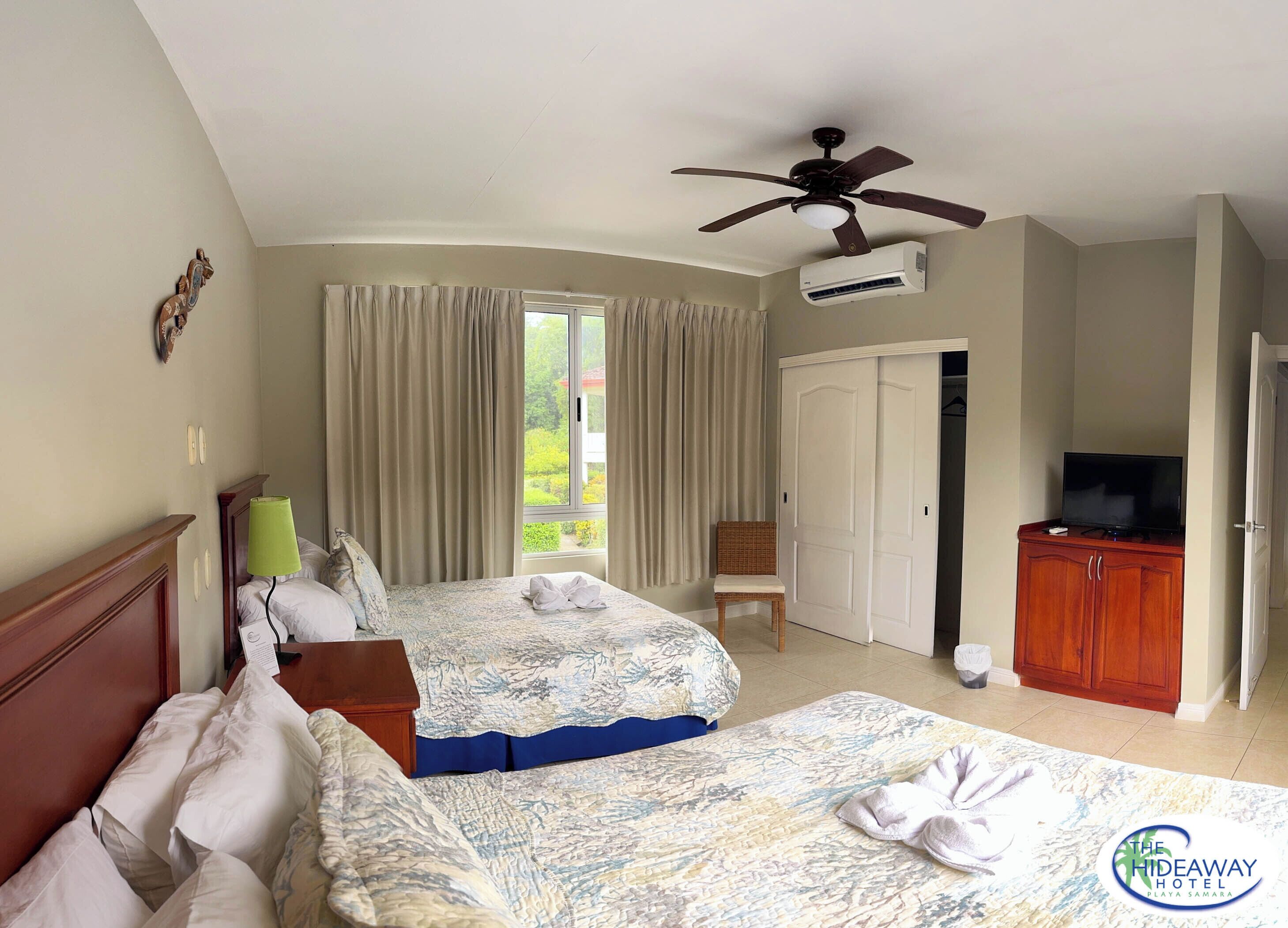 Una habitación de hotel con una cama, una silla, un televisor y un equipo de aire acondicionado.