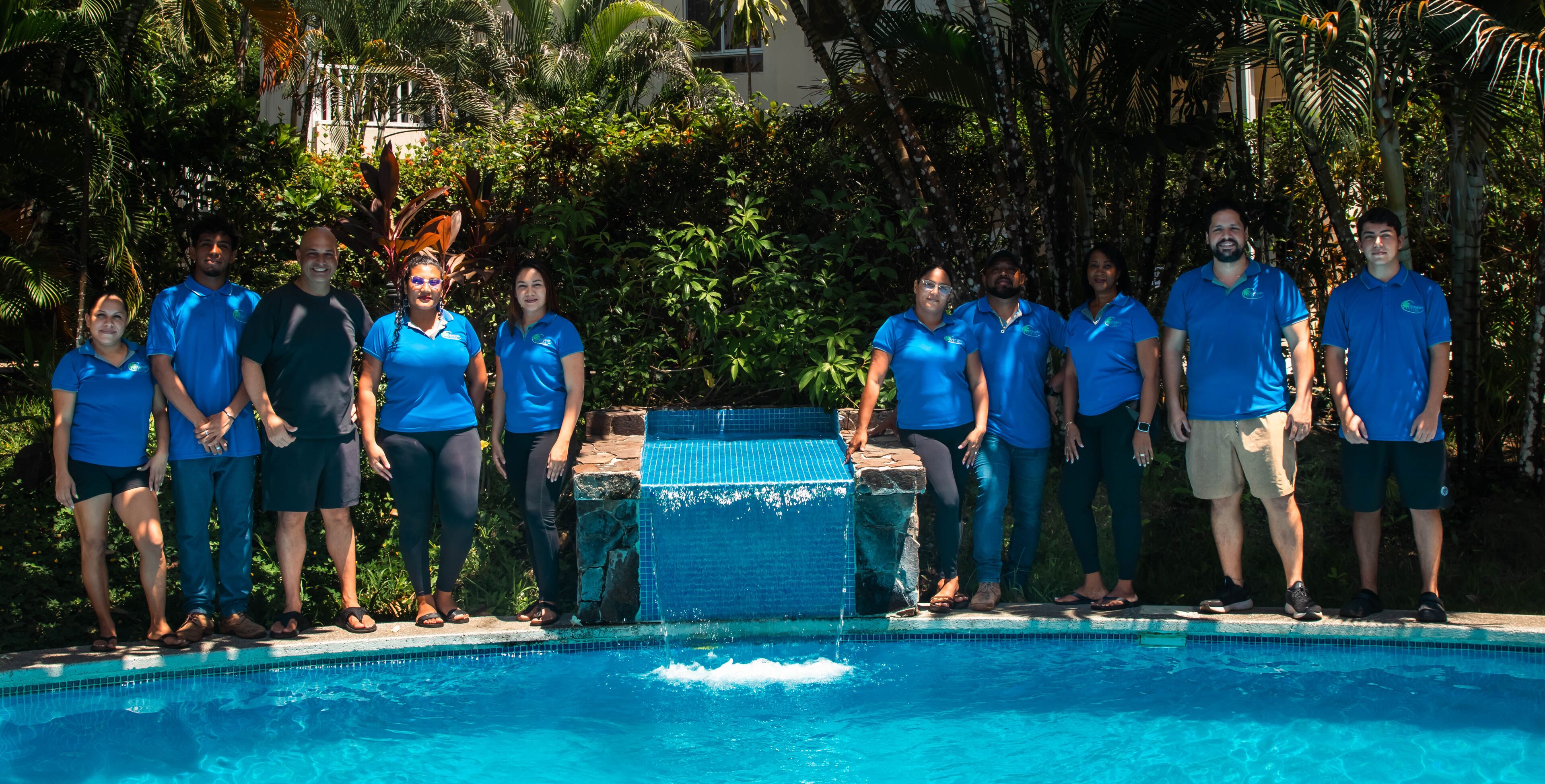 A group of people standing by a pool with a stone water feature in the center.