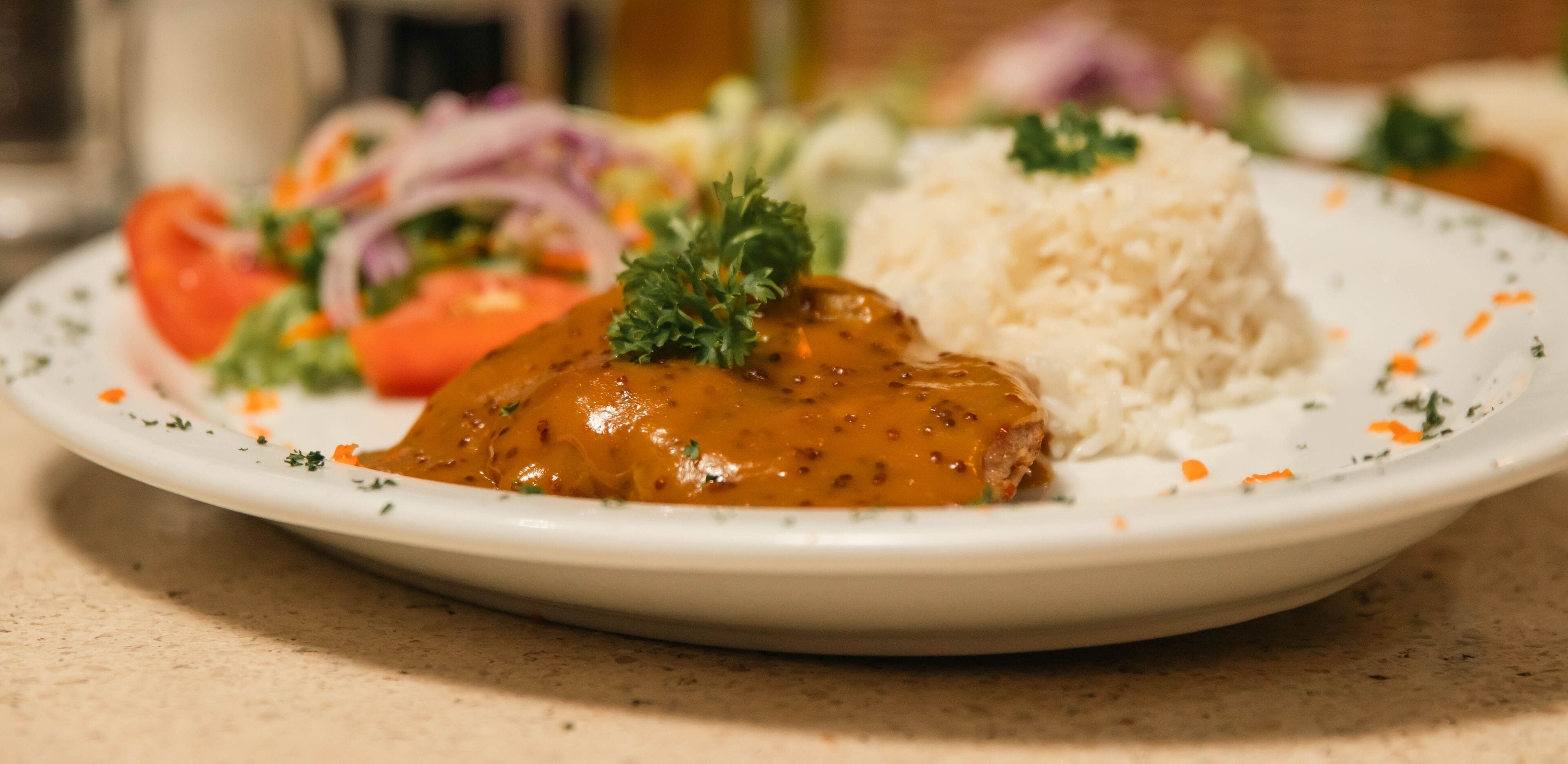 Un plato con un guiso de carne, arroz y ensalada.