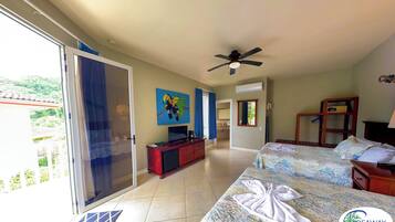 A hotel room with two beds, a TV, a ceiling fan, and a view of the outdoors.