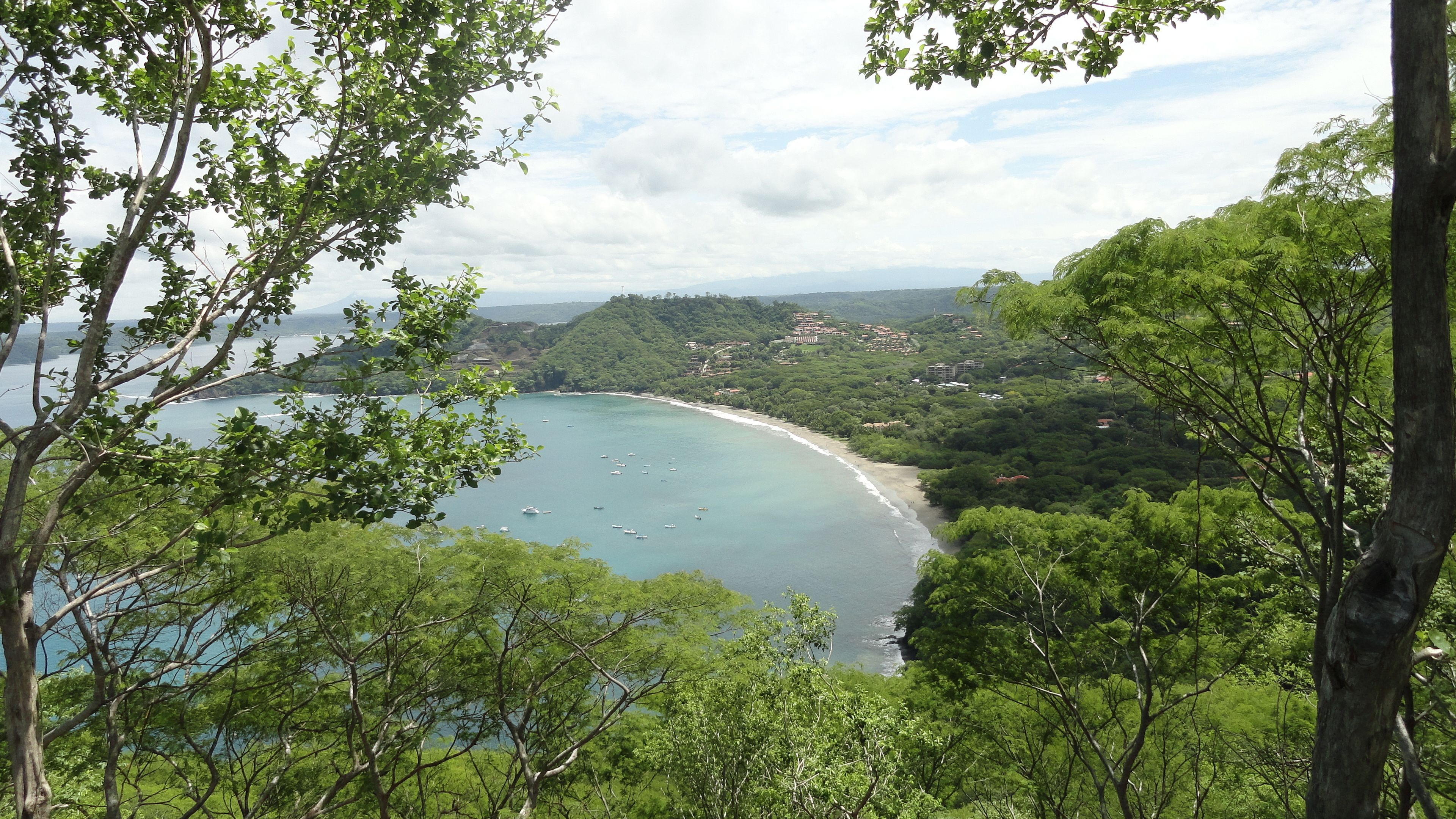 Un paysage côtier avec une plage, des bateaux et une végétation luxuriante.