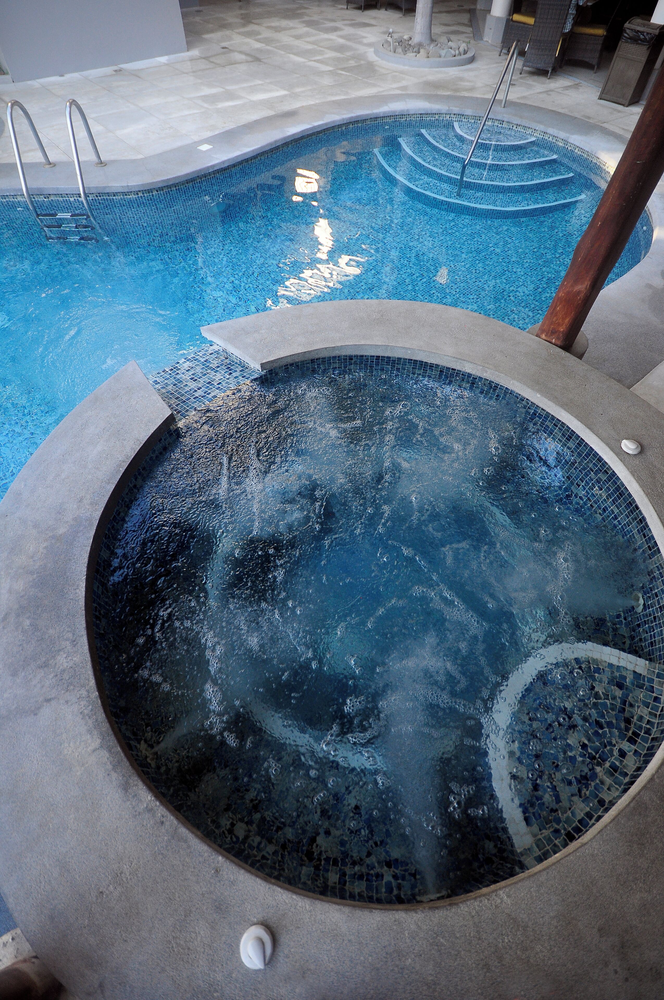 A hot tub with a tiled edge and a metal ladder.
