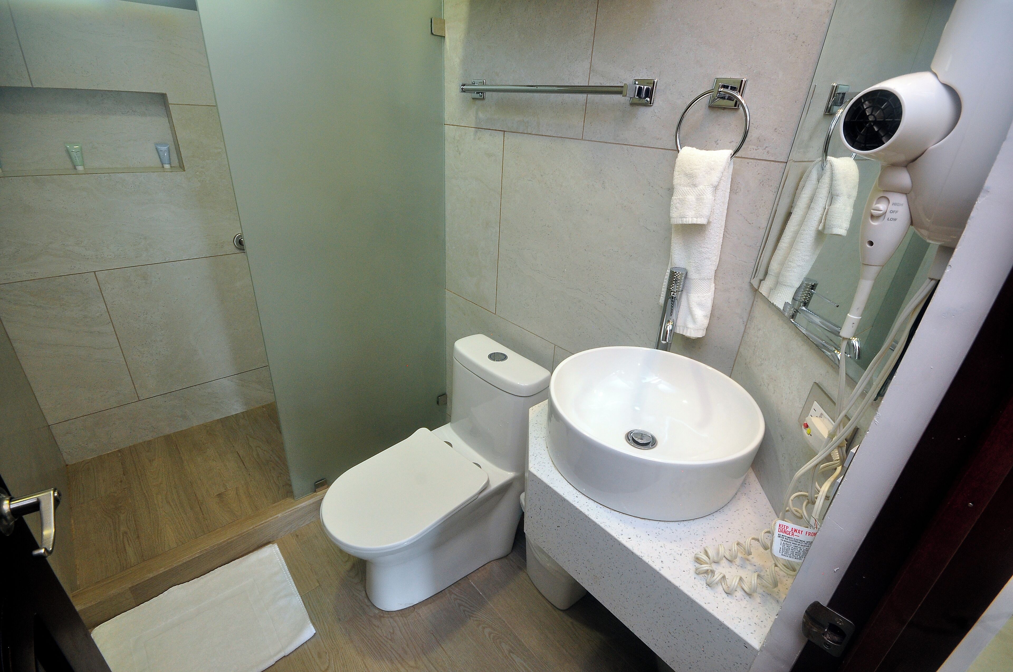 Un baño pequeño con inodoro, lavamanos y secador de pelo fijado a la pared.