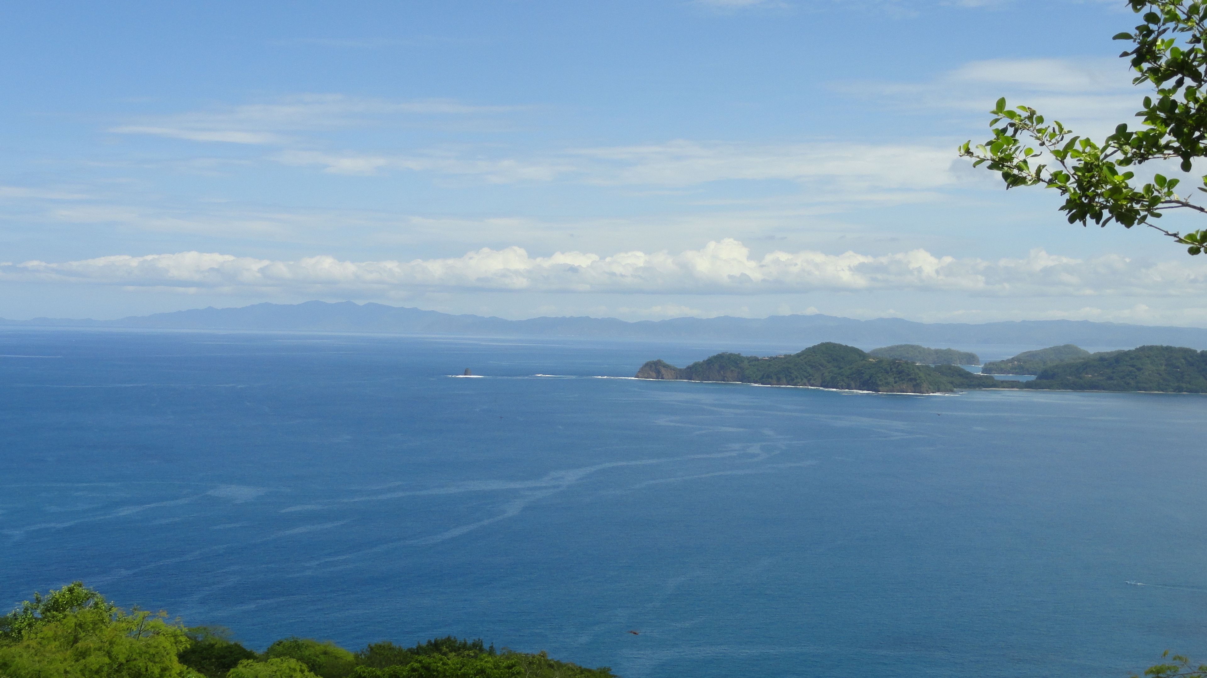 A coastal landscape with a view of the sea and distant mountains.